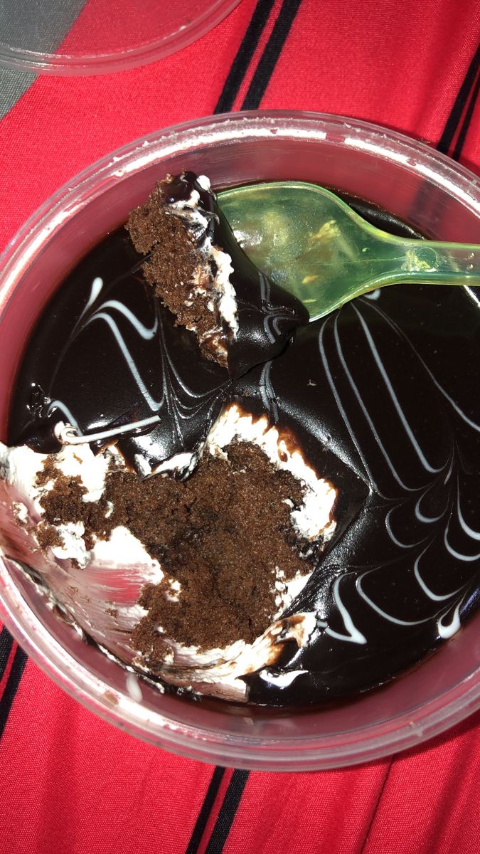 there is a chocolate cake with white frosting in a plastic bowl on the table