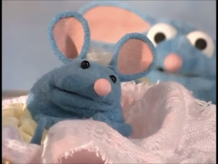 two blue stuffed mice sitting on top of a white cloth covered table next to each other