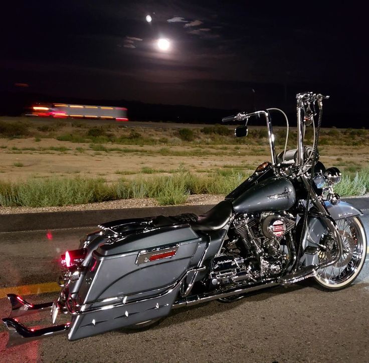 the motorcycle is parked on the side of the road in front of the moon and grass