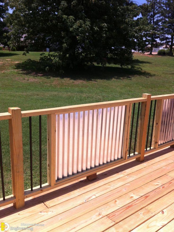 a wooden deck with metal railings and trees in the background