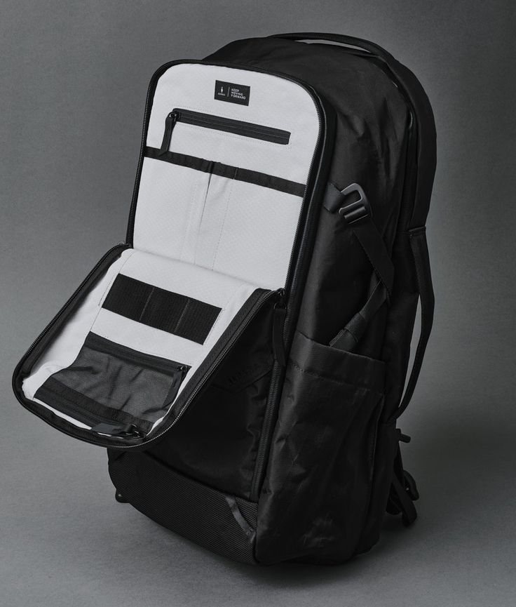 a black and white back pack on a grey background with the bottom section folded open