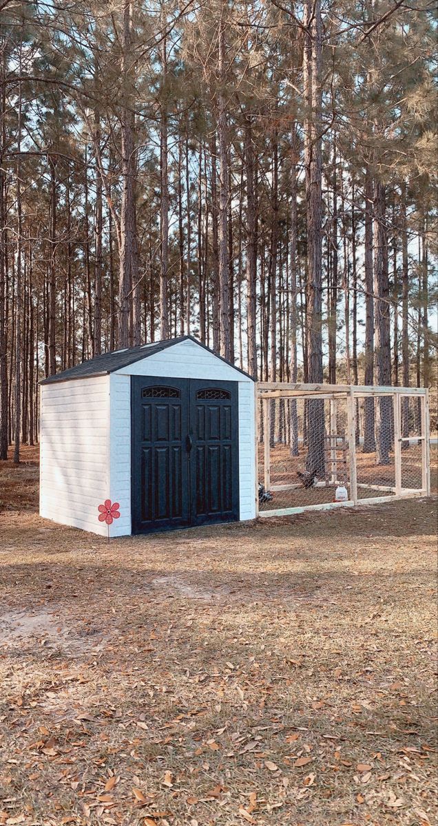 an outhouse in the middle of a forest with a chicken cage on it's side