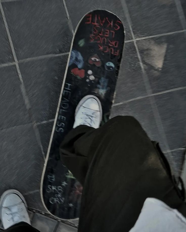 a person standing next to a skateboard on a tiled floor with graffiti written on it