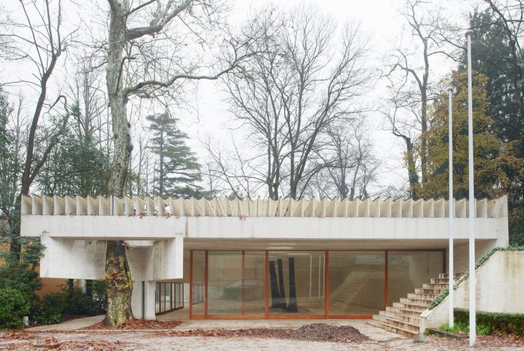 a white building with stairs leading up to it's entrance and trees in the background