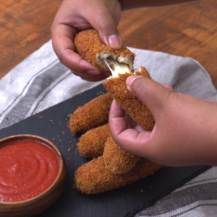 someone is dipping something into some kind of fried chicken nugget with ketchup on the side