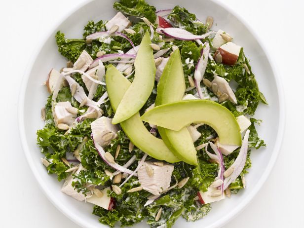 a white bowl filled with greens and sliced apples