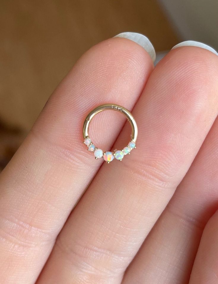 a woman's hand holding a gold ring with three stones on the inside of it