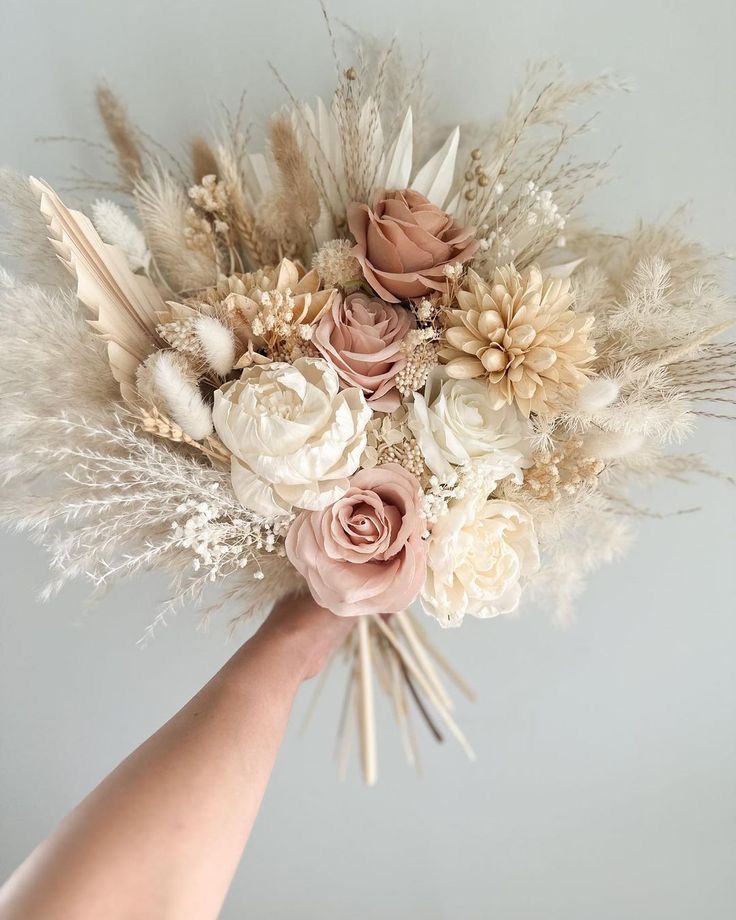 a hand holding a bouquet of flowers and feathers