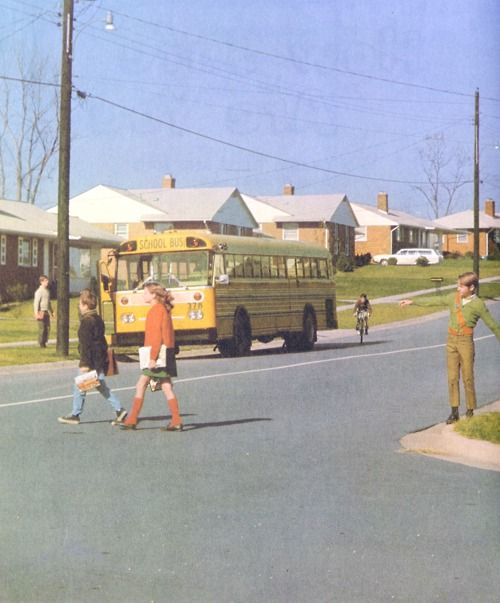 several children are crossing the street in front of a school bus and some people on skateboards