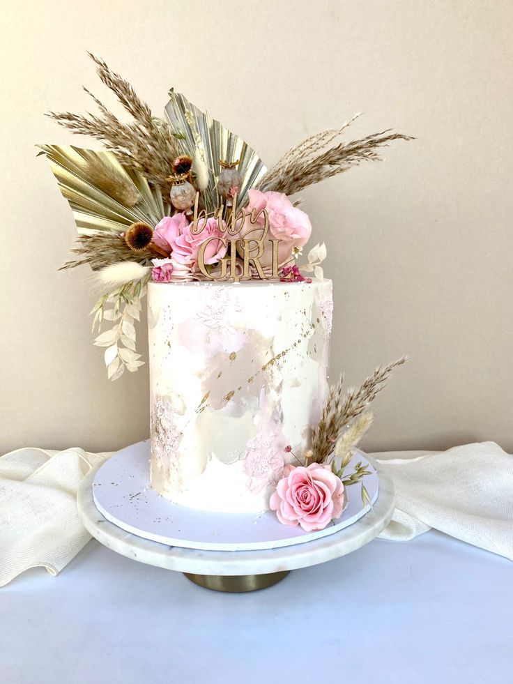 a white cake with pink flowers and greenery on top