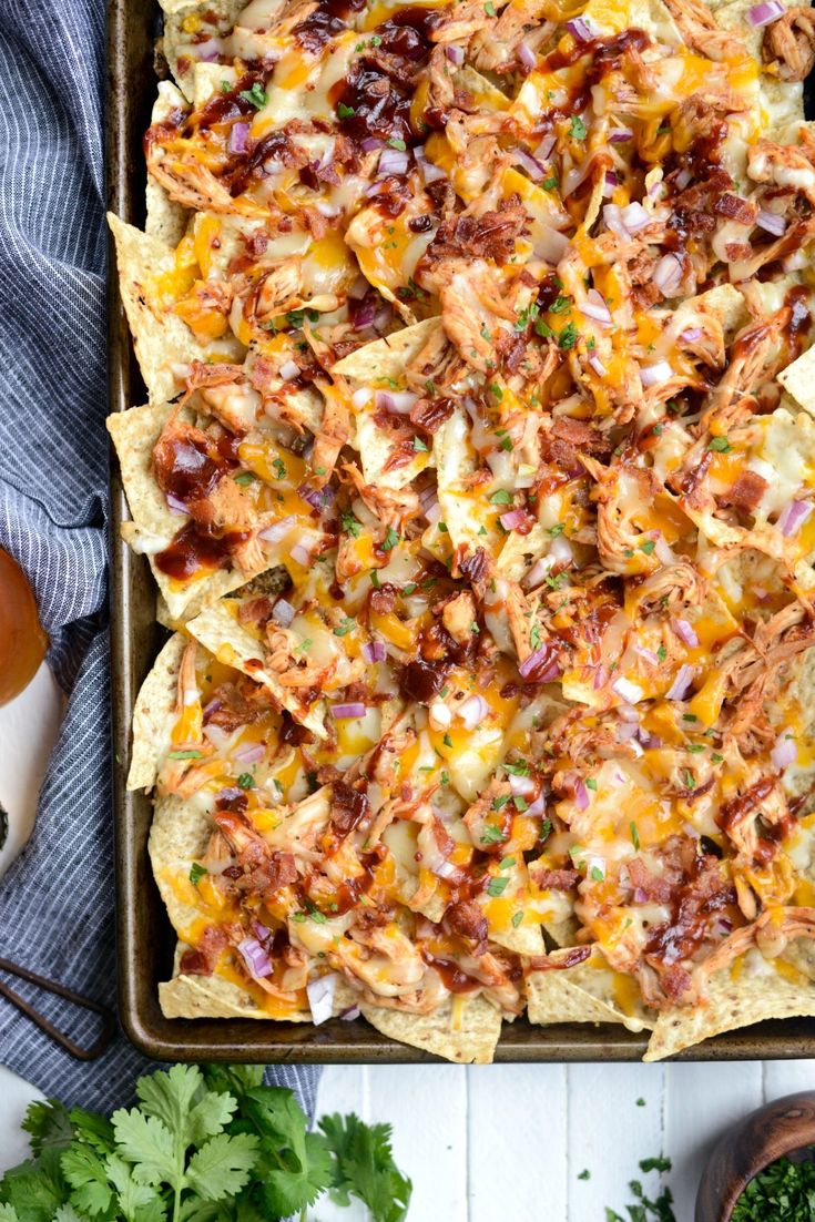 an overhead view of nachos in a baking dish with toppings on the side