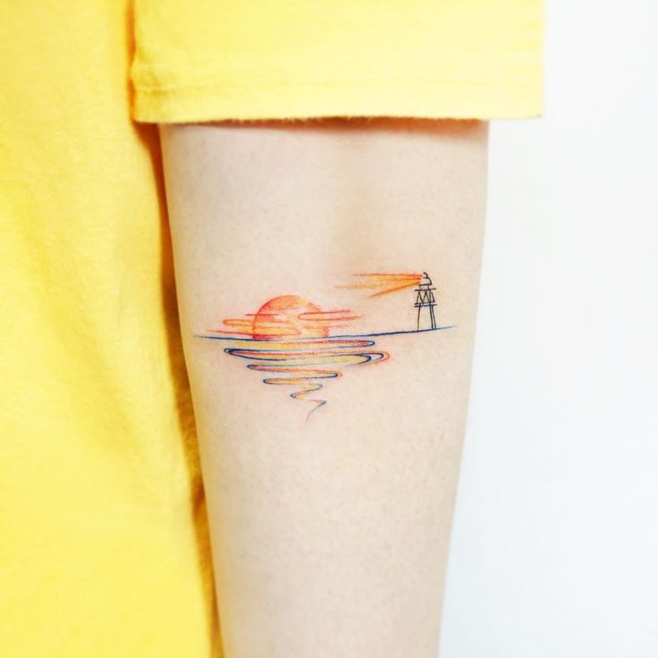 a woman's arm with a small lighthouse tattoo on the left side of her right arm