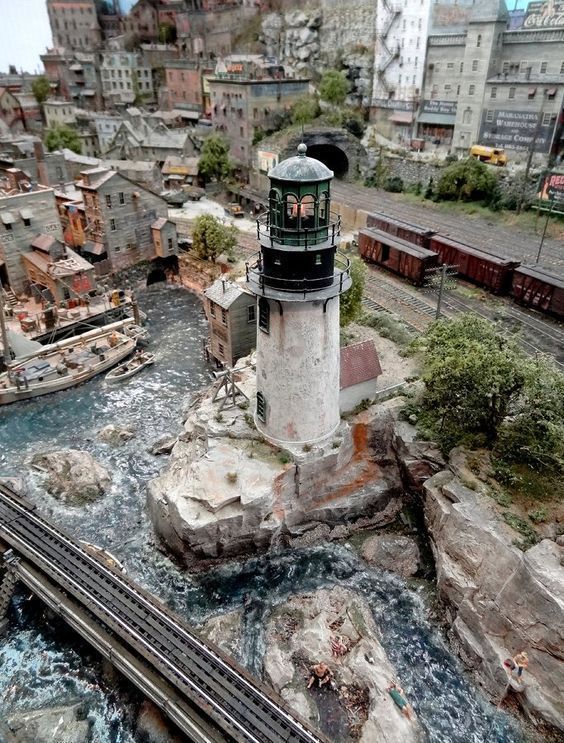 an aerial view of a train track and a light house in the middle of town