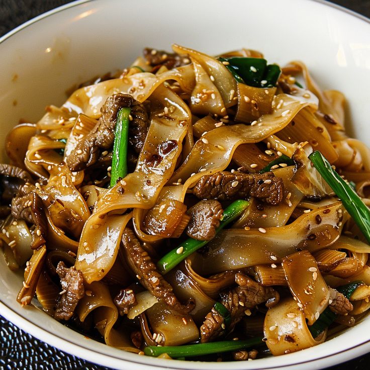 a white bowl filled with noodles and meat