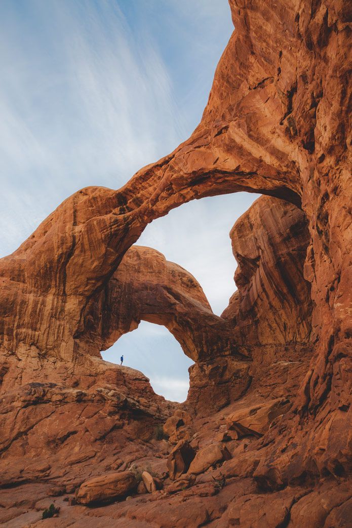 a person standing in the middle of a rock formation with an arch shaped like a human head