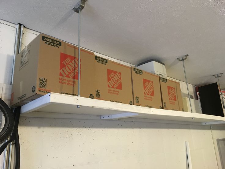 boxes are stacked on top of each other in a storage room with a fan hanging from the ceiling