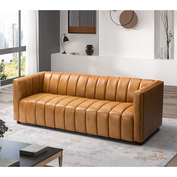 a brown leather couch sitting on top of a carpeted floor next to a window