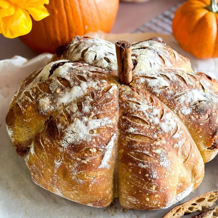 a loaf of bread sitting on top of a table next to pumpkins and other food