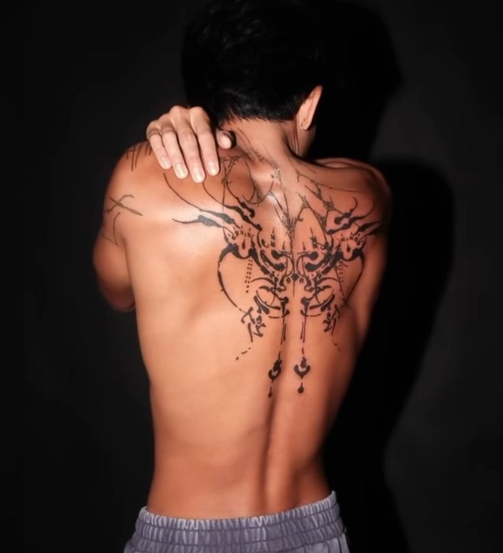 the back of a man with tattoos on his upper and lower half is shown in front of a black background