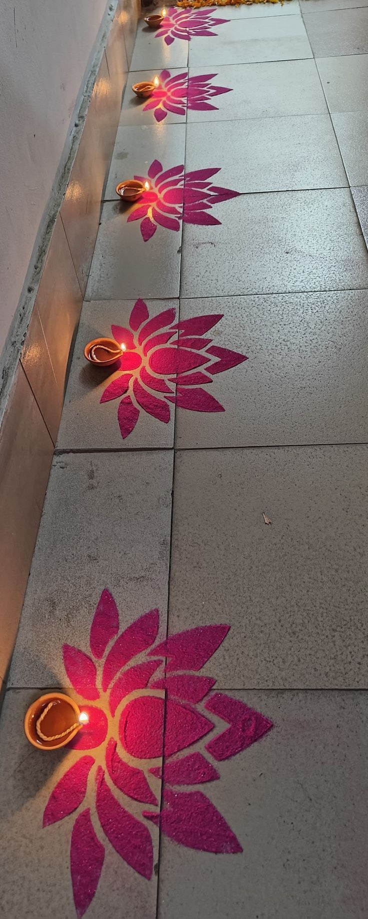 some lights are lit up on the ground with flowers painted on them in pink and orange