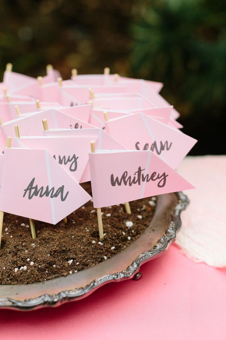 there are many pink signs on top of the cake that is decorated with dirt and grass