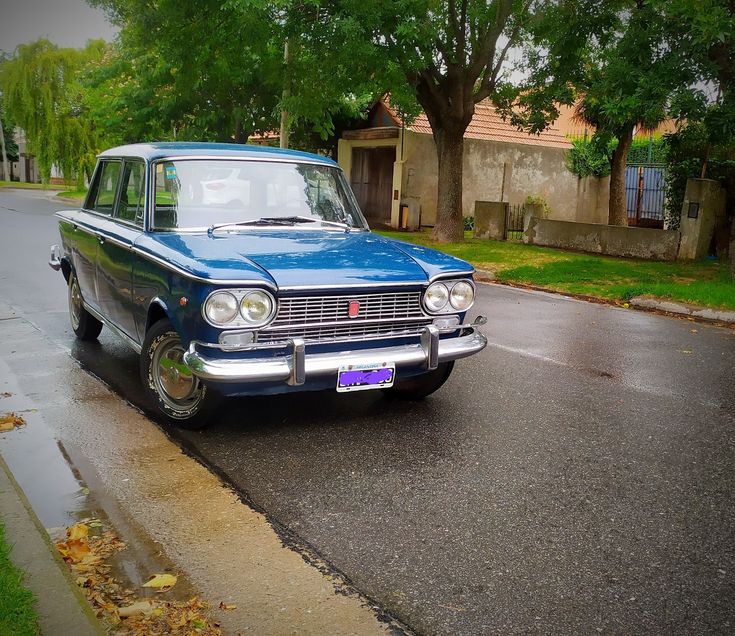 an old car is parked on the side of the road in front of a house