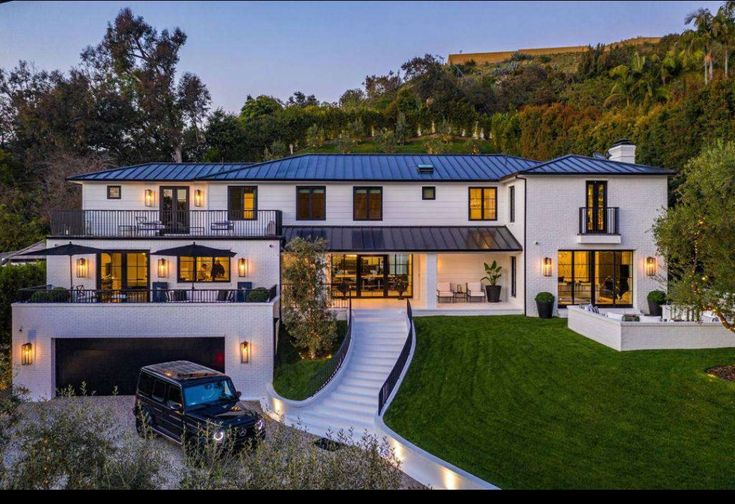 a large white house sitting on top of a lush green hillside