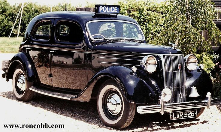 an old police car parked in front of some bushes