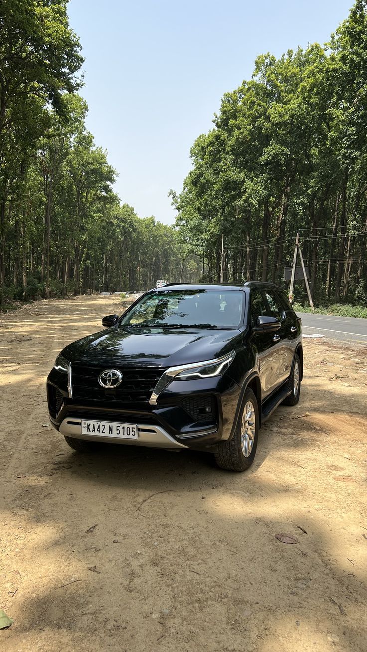 a black suv parked in the middle of a dirt road