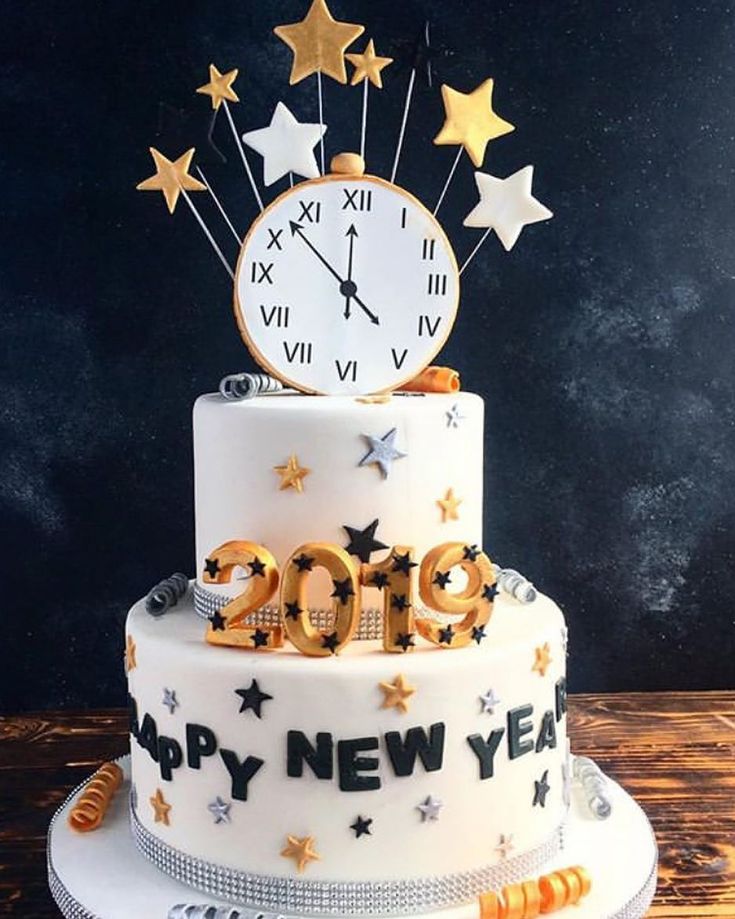 a white cake with gold stars and a clock on top that says happy new year