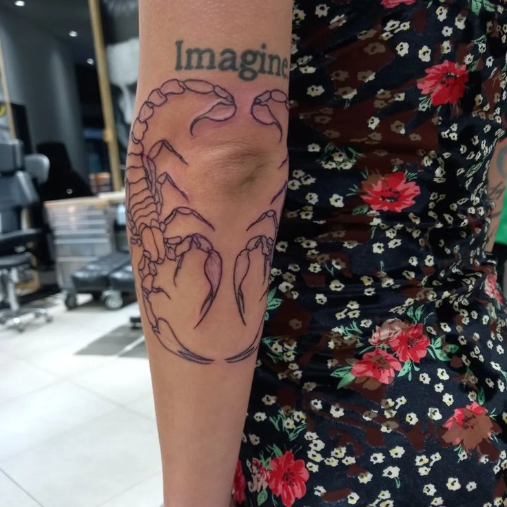 a woman with a crab tattoo on her arm and the word imagine written in it