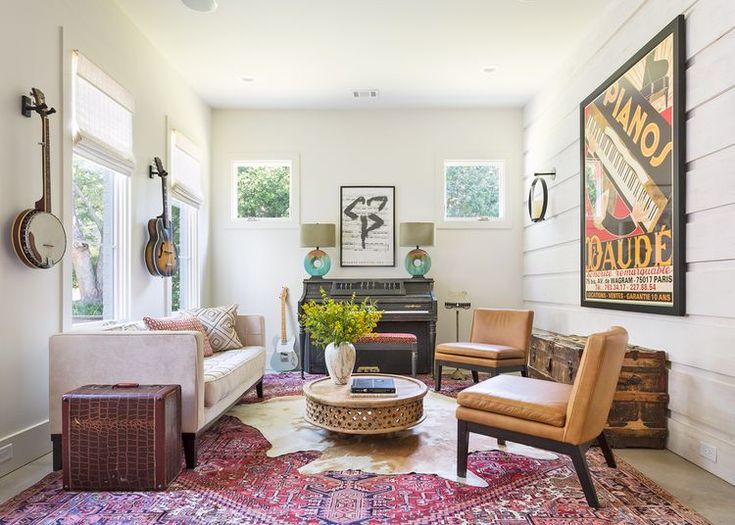 a living room filled with lots of furniture and paintings on the wall above it's windows