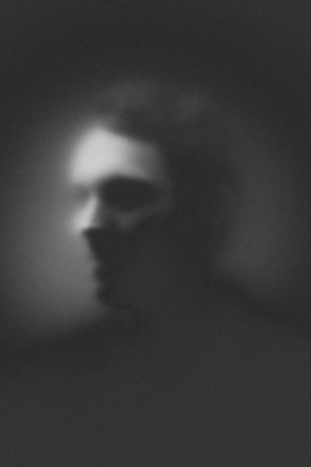 a blurry image of a man's face in the middle of a dark room