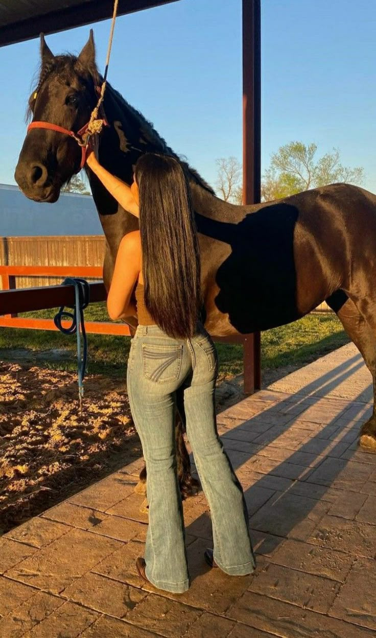 a woman standing next to a brown and black horse