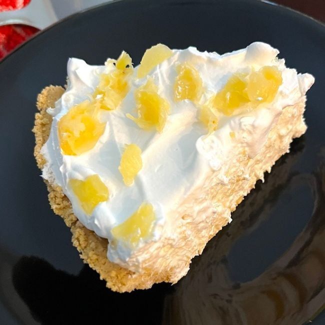 a piece of cake on a black plate with lemons and whipped cream frosting