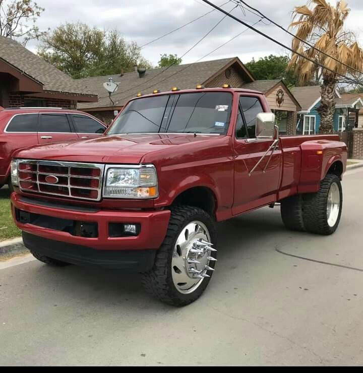 a red pick up truck parked on the side of a road in front of some houses