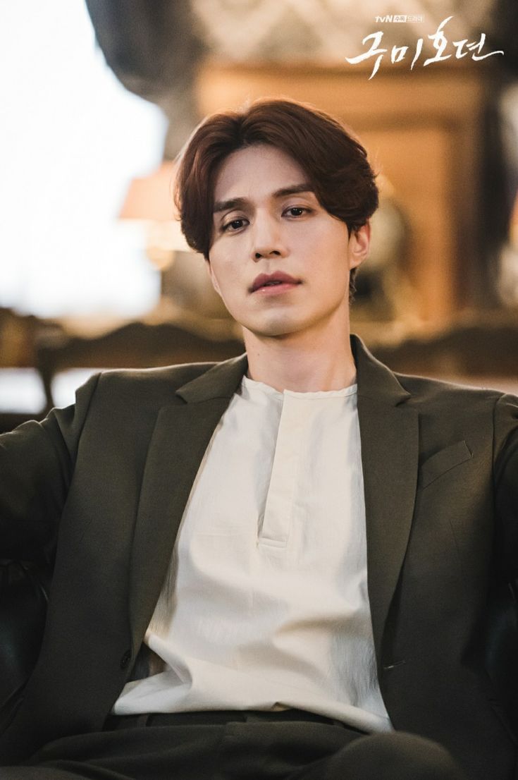 the young man is sitting in a chair wearing a suit and white shirt with black pants