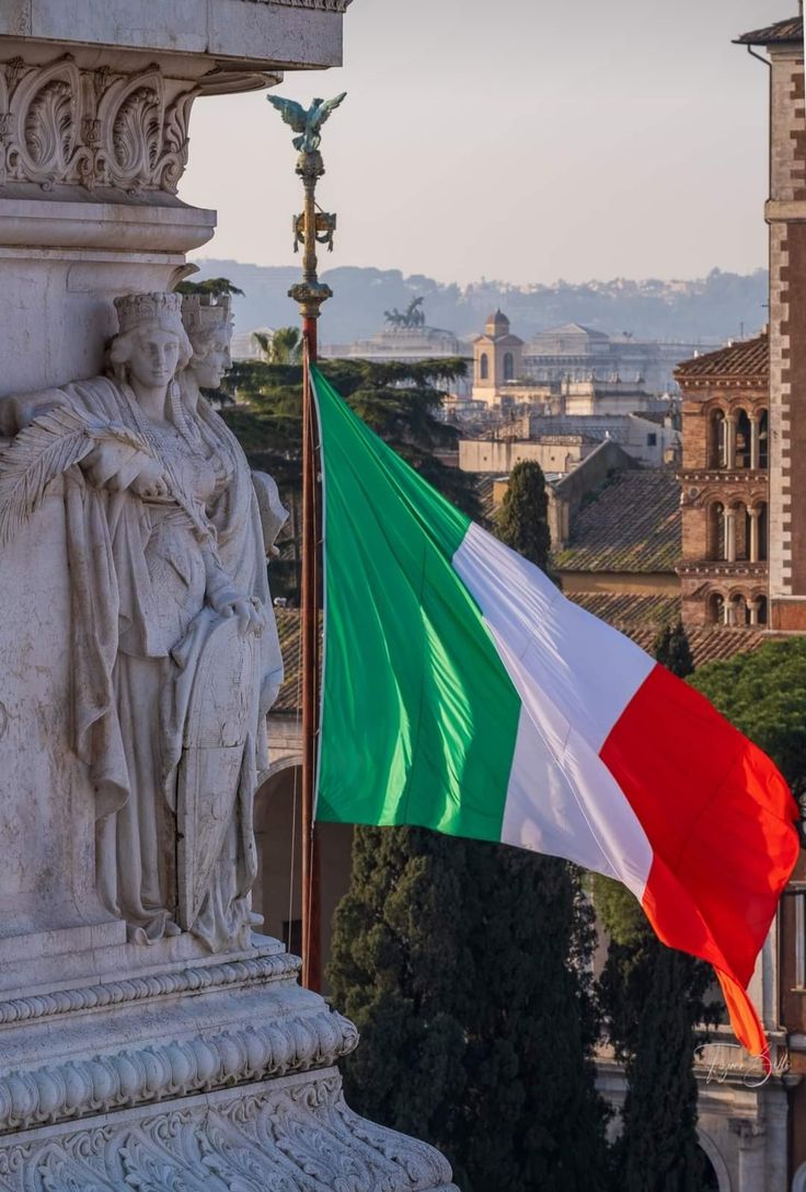 an italian flag flying in front of a statue