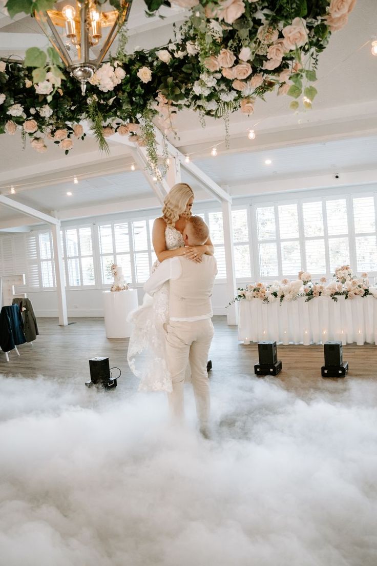 a woman holding a baby in her arms while standing on top of cloud covered floor