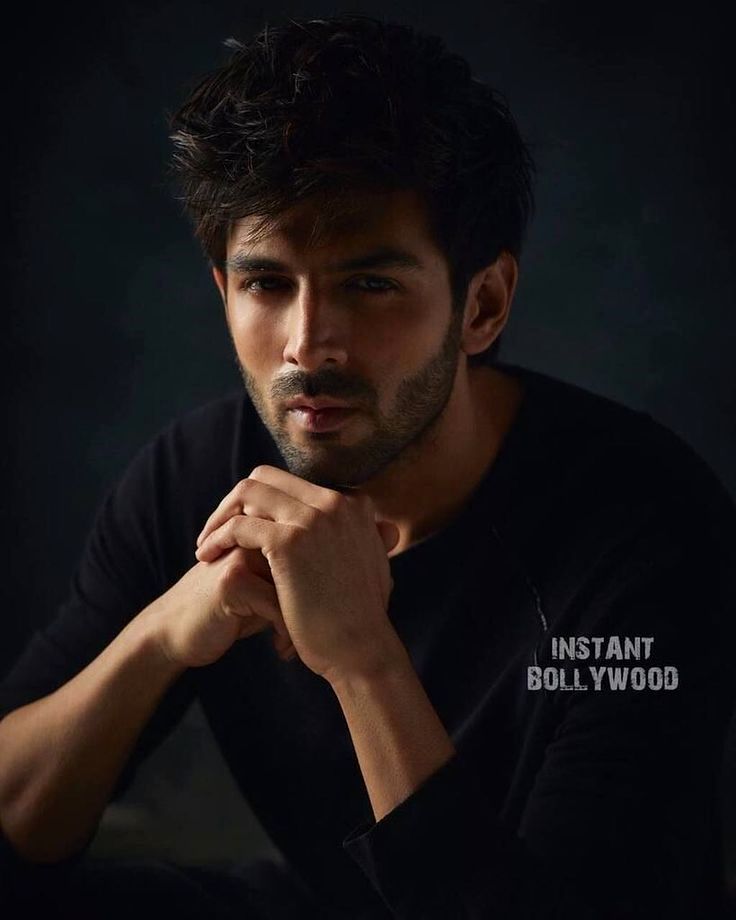 a man sitting down with his hand on his chin and looking at the camera while wearing a t - shirt that says instant bollywood