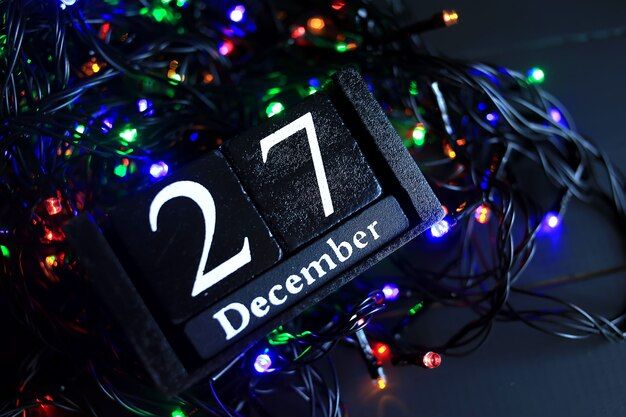 a black calendar with the date on it surrounded by christmas lights and garlands that reads, december 27