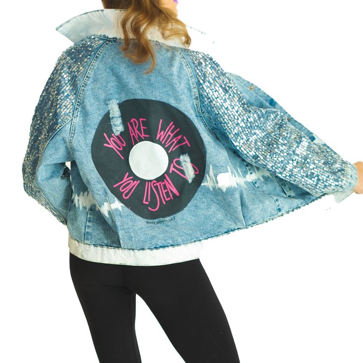 DESCRIPTION Updated branding comes with updated W+G Classics! Our limited edition version of our Best-Selling 'With The Band' jacket is here for a limited time! Denim jacket with sequins down the sleeves. Large black record painted on back, with YOU ARE WHAT YOU LISTEN TO painted in bright pink on the record. Collar and bottom hem painted white. Sounds wave painted across entire body of jacket in white. Signed @wrenandglory. Due to each piece being hand painted, each jacket might have slight differences. EACH PIECE IS MADE TO ORDER, HAND PAINTED BY GLORIA AND HER TEAM IN THEIR NYC STUDIO FIT Lighter weight denim jacket with silver sequins going down the sleeves. Comfortable denim. ONE SIZE FITS MOST! (XS - L) MEASUREMENTS: Bust 120cm, Length 67cm, Sleeve 73cm. Casual Denim Outerwear With Sequins, Denim Sequined Outerwear For Fall, Trendy Denim Jacket With Sequins, Casual Long Sleeve Denim Jacket With Sequins, Trendy Long Sleeve Denim Jacket With Sequins, Winter Long Sleeve Denim Jacket With Sequins, Trendy Long-sleeve Denim Jacket With Sequins, Casual Spring Outerwear With Sequins, Casual Sequined Outerwear For Spring