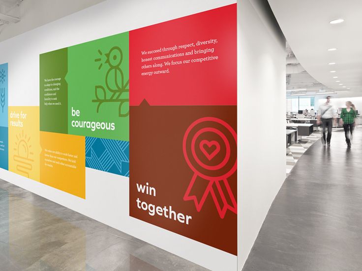 an office lobby with large colorful banners on the wall and people walking in the background