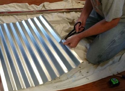 a person cutting metal sheet with scissors on the floor