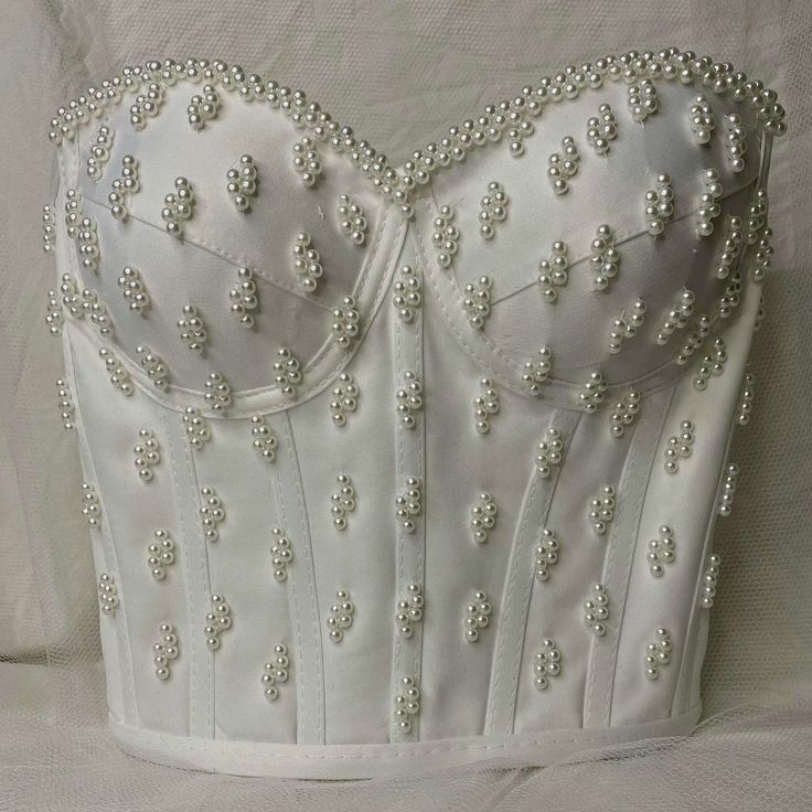 Looking for something truly special for your big day? This handmade satin corset top is a dreamy choice for brides who want to stand out. Adorned with hand-applied pearls and crafted with care, it's perfect for weddings, after-parties, or even a chic civil ceremony. The soft satin fabric feels luxurious on the skin, while the lace-up back gives you a snug and flattering fit. Whether you pair it with a flowing skirt for a classic bridal look or style it with tailored trousers for a modern vibe, t Pearl Corset Top, Madam Pompadour, Bridal Corset Top, After Party Dress, Bridal Bustier, Bead Bra, White Corset Dress, Sparkly Fashion, Wedding Corset