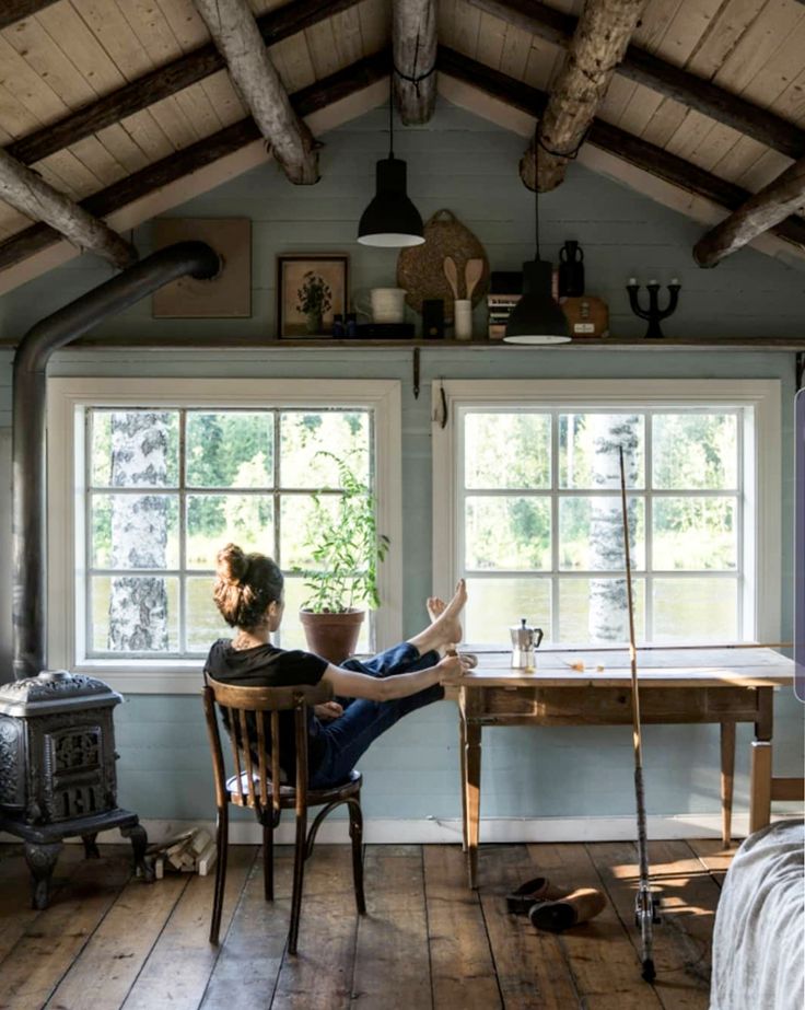 a woman sitting at a table in front of a window with tools on the windowsill