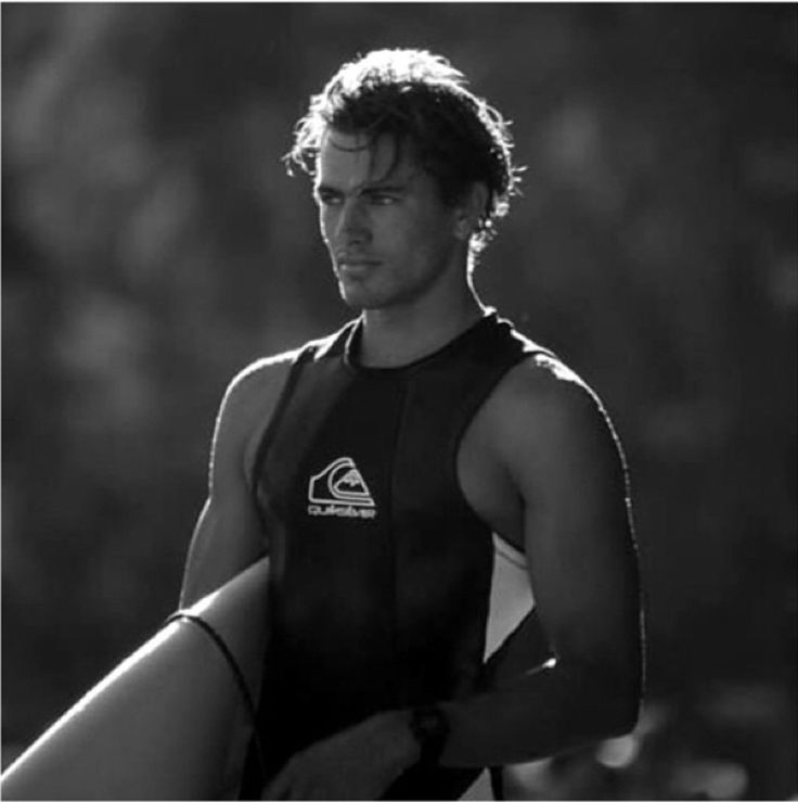 a man holding a surfboard while wearing a wet suit