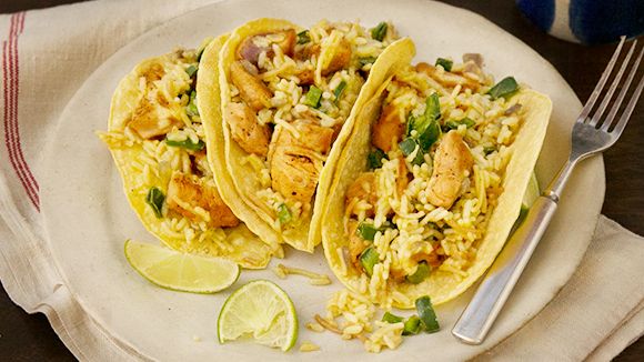 two tacos with chicken and rice on a plate