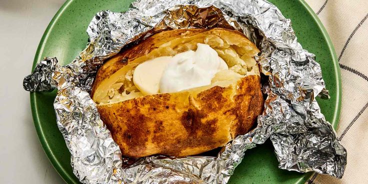 a green plate topped with food covered in foil