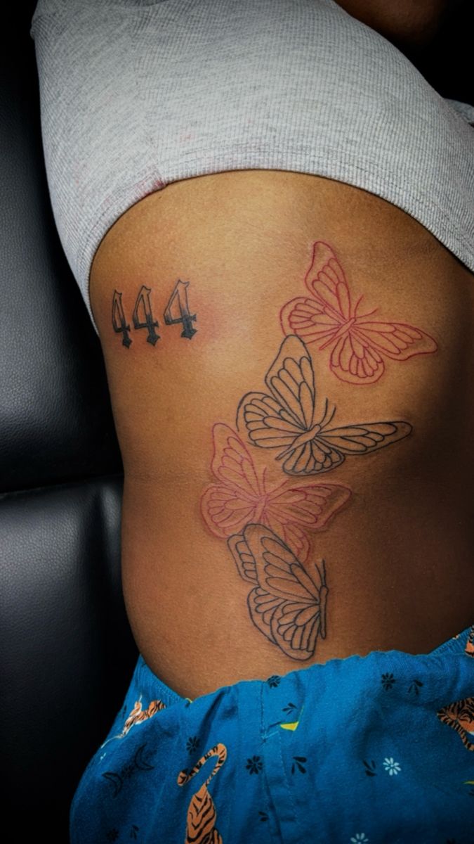 a woman's stomach with butterflies and numbers tattooed on the bottom part of her belly